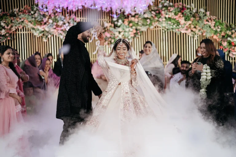 Bride and groom exchanging smiles on floral-decorated stage