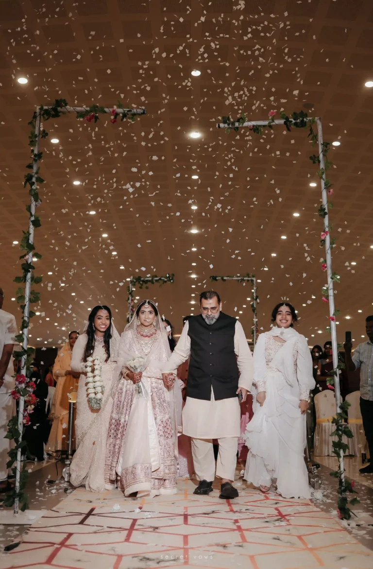 Bride holding hands with parents while walking to the wedding stage