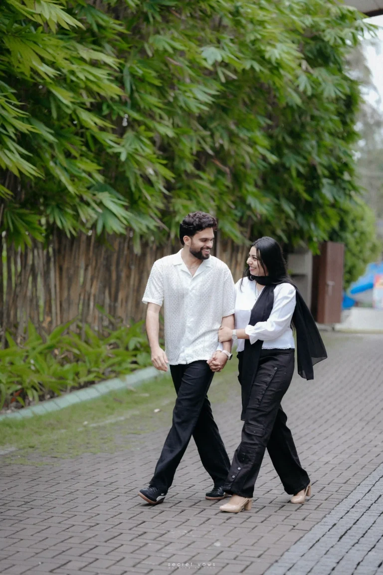 Couple walking hand-in-hand under decorative lights at an outdoor venue.