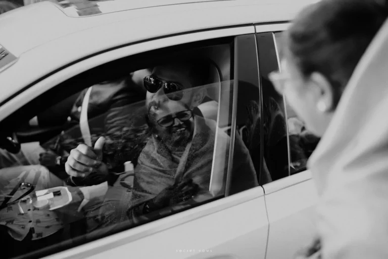 Groom stepping out of car with smiling welcome from bride’s relatives