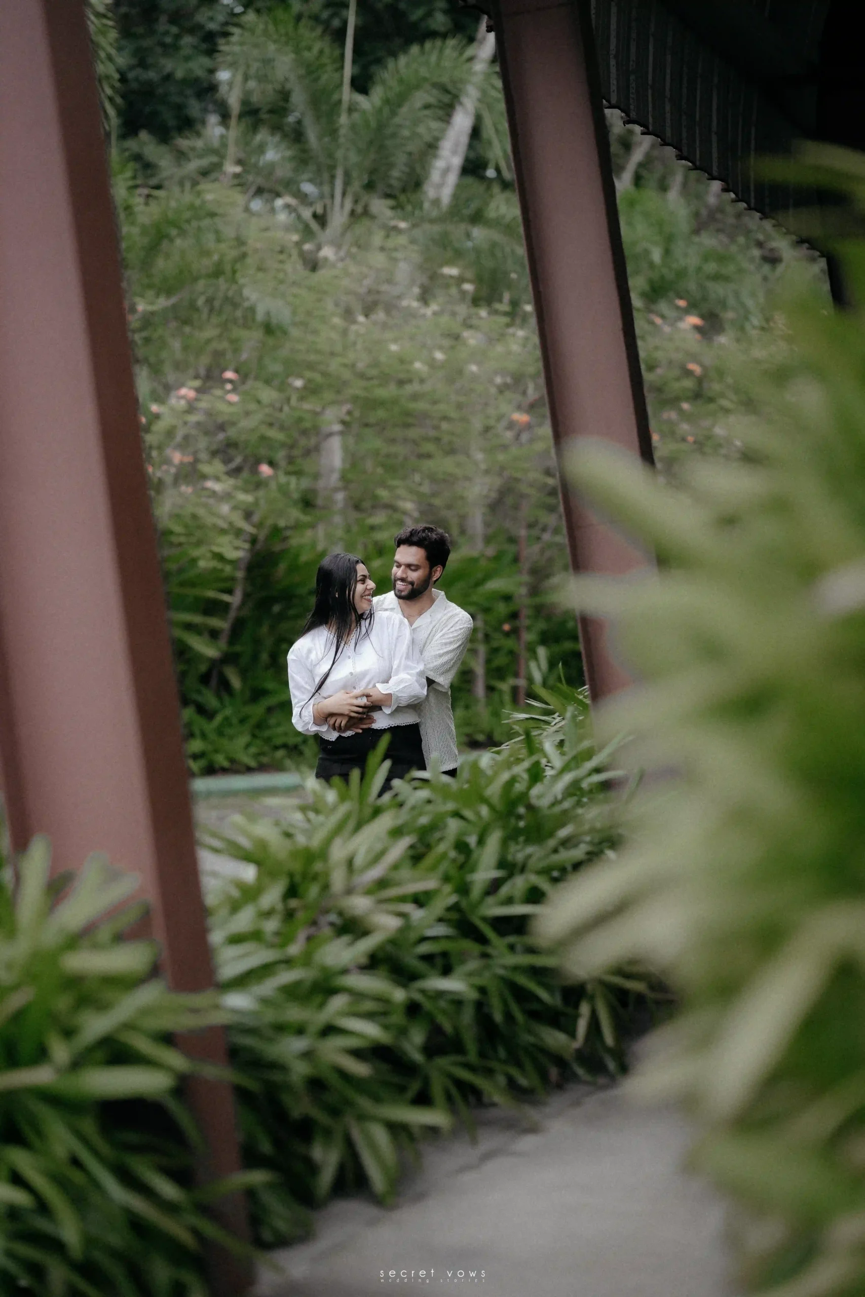 Romantic outdoor photography session featuring a couple in matching white outfits in a tropical garden setting
